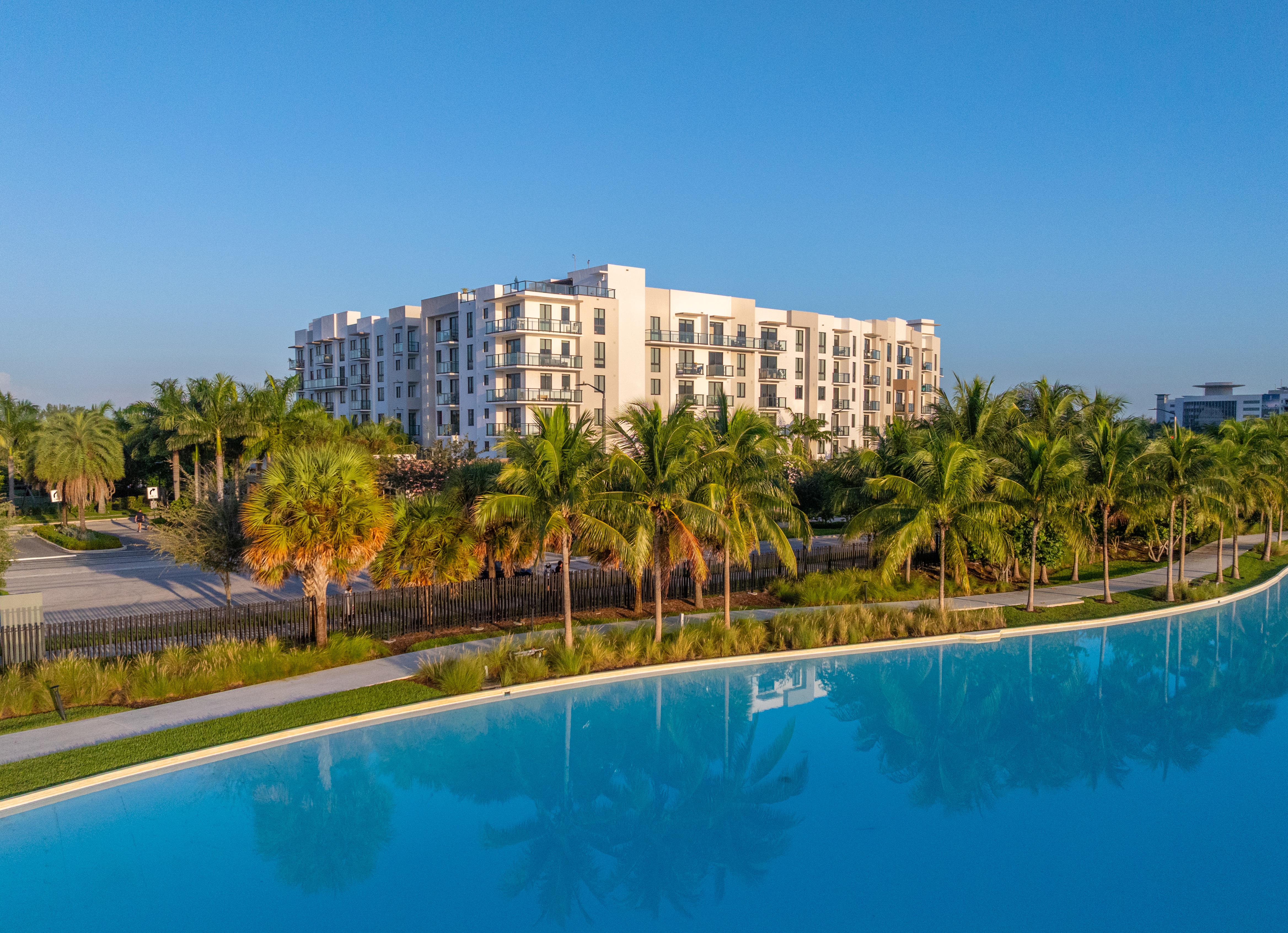 A large white building with a pool in front of it.